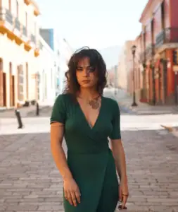 Stylish woman in green dress standing on colorful city street.